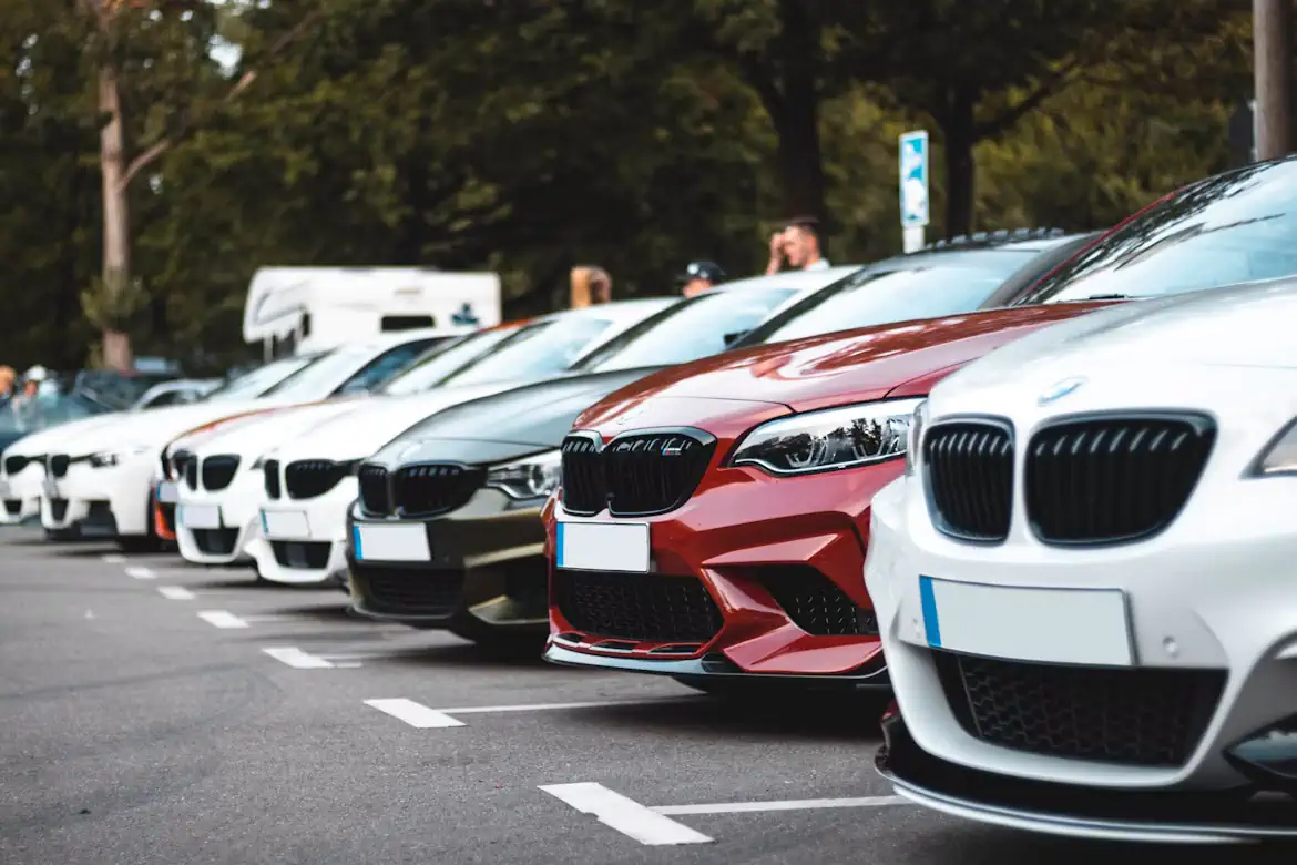 Stāvvietā rindā novietoti dažādu krāsu BMW automobiļi.